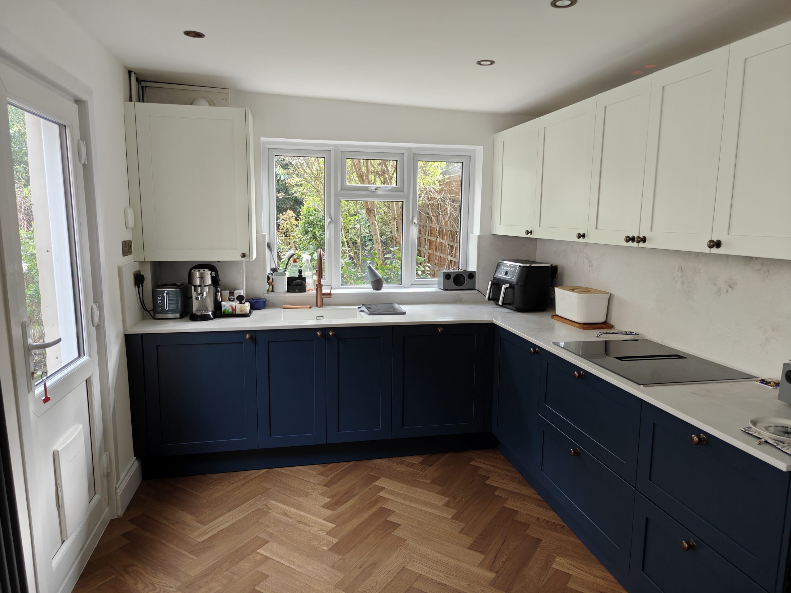 Full view of completed Hague Blue and Blizzard White Caledonia Kintyre kitchen, Stone Sense quartz worktops, Charlton SE7