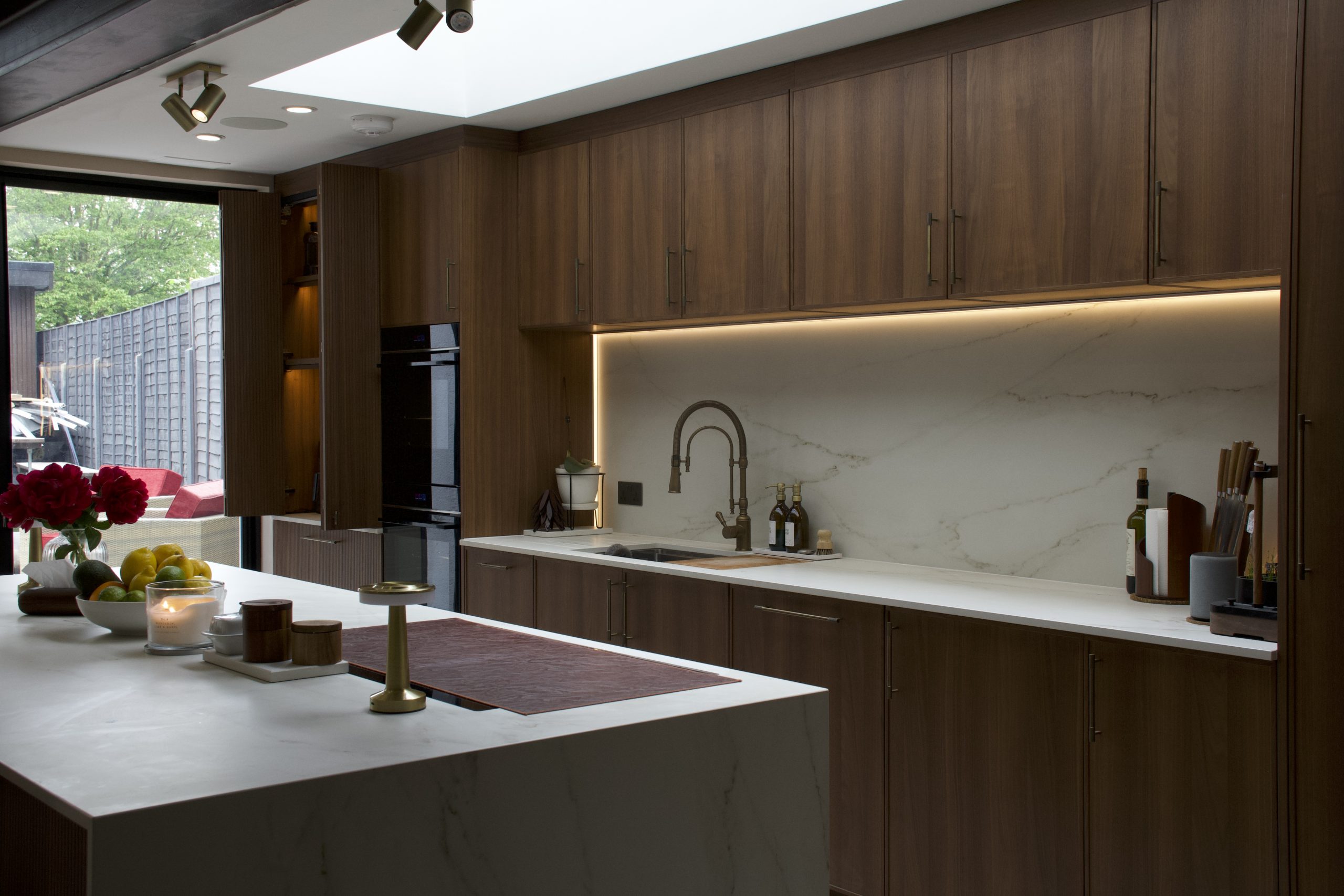 Rotpunkt walnut kitchen with Dekton worktops and glass-fronted dresser, designed by Victoria Kitchens, SE London
