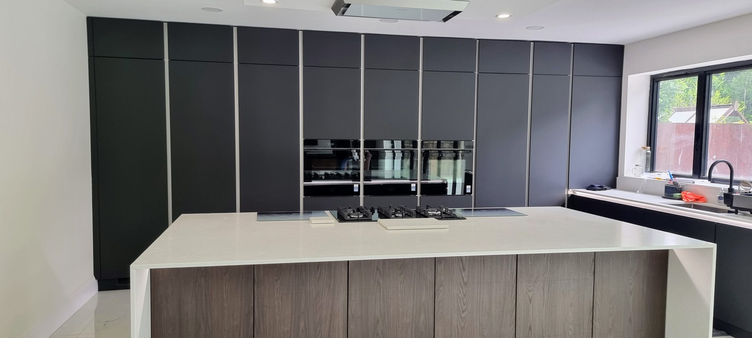 Dark carbon matt kitchen with integrated wood-effect panel detail and handleless cabinetry, Victoria Kitchens, Bexley
