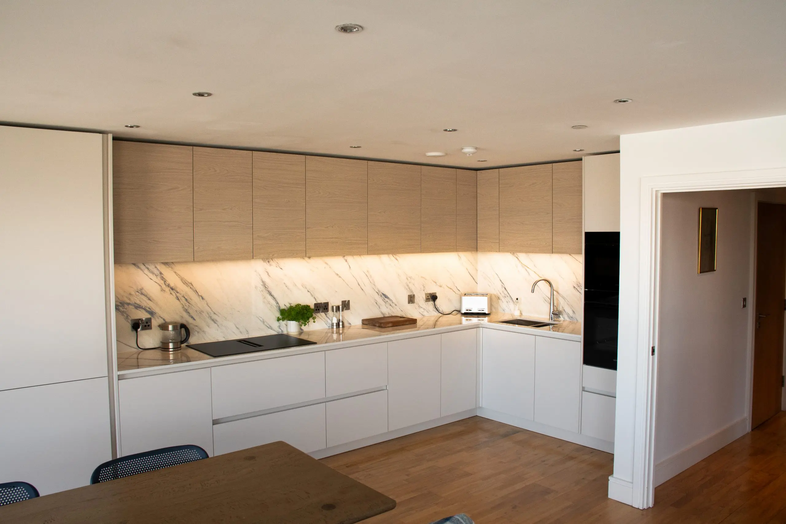 Cashmere handleless open-plan kitchen showing full run of cabinetry, Victoria Kitchens, Greenwich