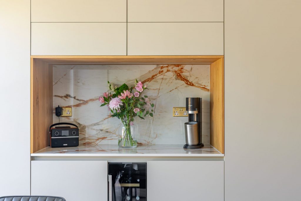 Wide view of integrated wine cooler and open display niche with flowers in a Rotpunkt cashmere kitchen, Victoria Kitchens