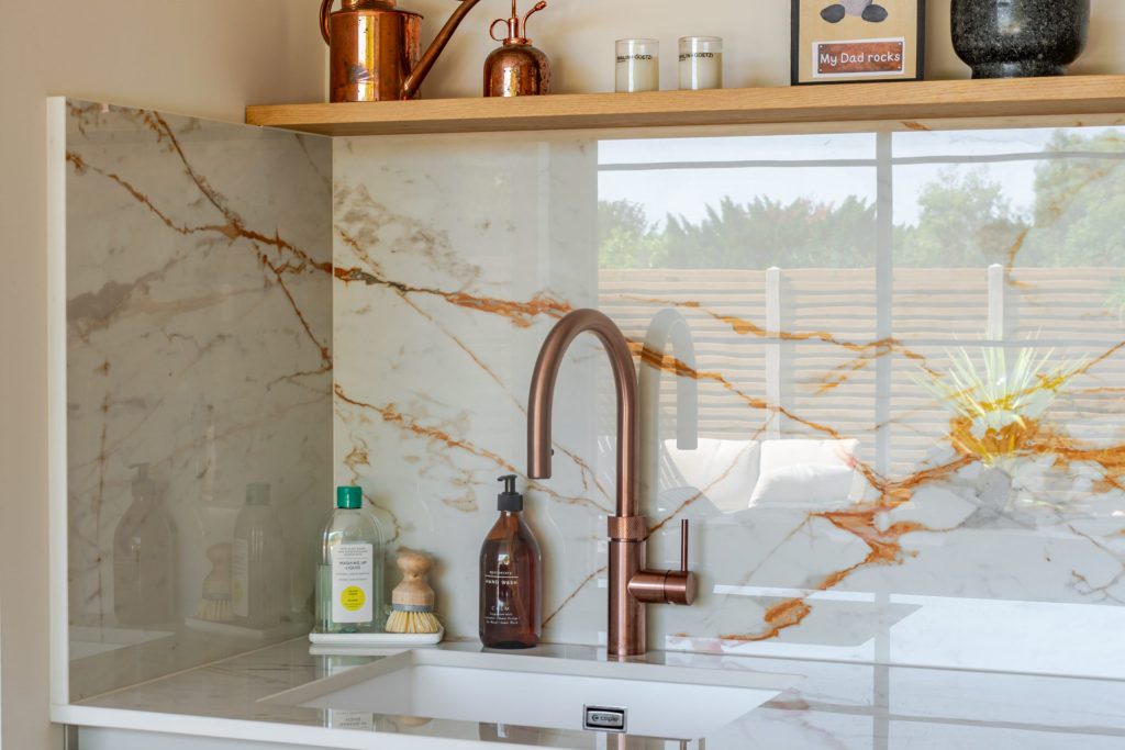 Angled shot of Quooker boiling water tap and Caple sink with Dekton worktop, splashback and floating shelves, Rotpunkt kitchen, Victoria Kitchens
