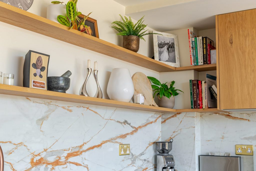 Wide view of Rotpunkt oak veneer cabinet corner with Dekton splashback and styled floating shelves, Victoria Kitchens