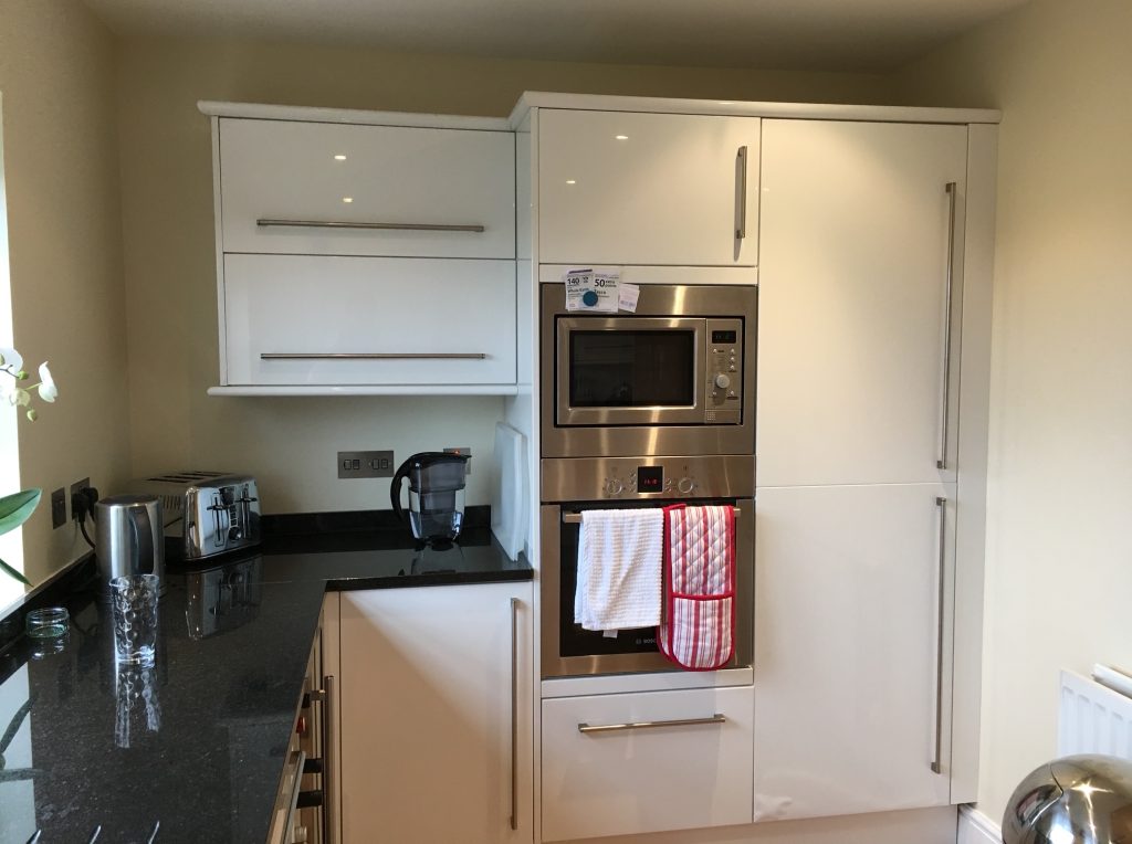 Tired white, glossy kitchen with handles, before the Victoria Kitchens renovation