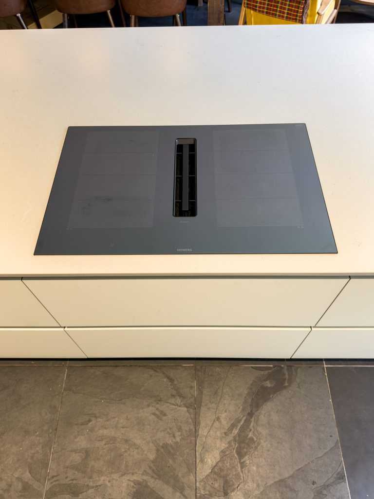 Close-up of integrated hob set into Rotpunkt kitchen island with Kashmir Matt and timber surround, Victoria Kitchens