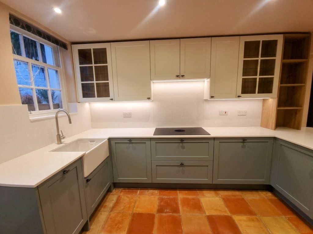 Kitchen overview showing sink under window with tap, two-tone shaker cabinetry and uninterrupted cooking run, Victoria Kitchens