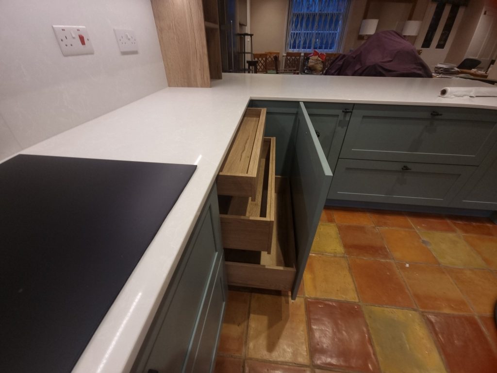 Slide-out cabinet with three solid oak drawers pulled partially open, showing internal kitchen storage, Victoria Kitchens